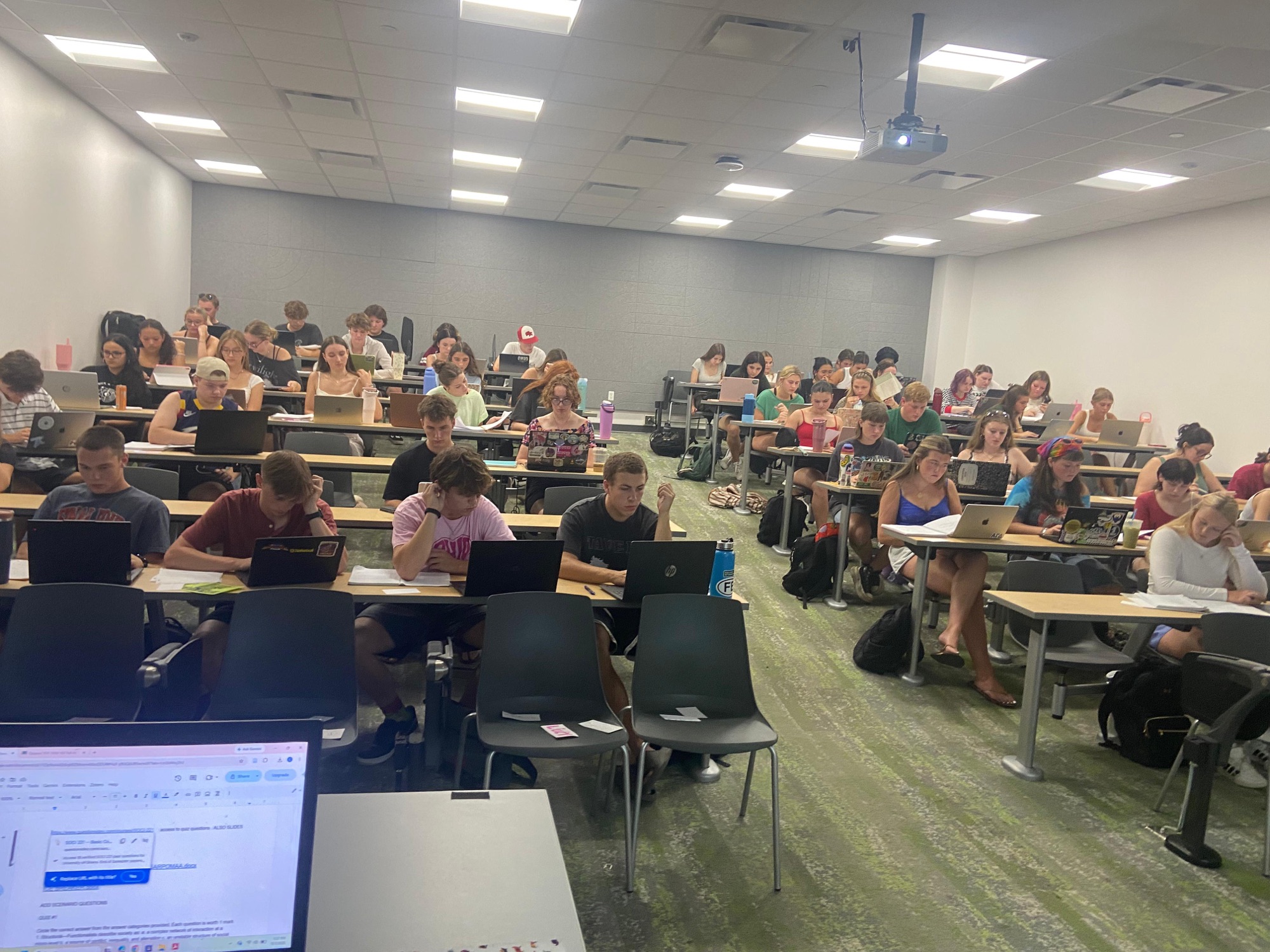 A full classroom of students reading, writing, and working on laptops