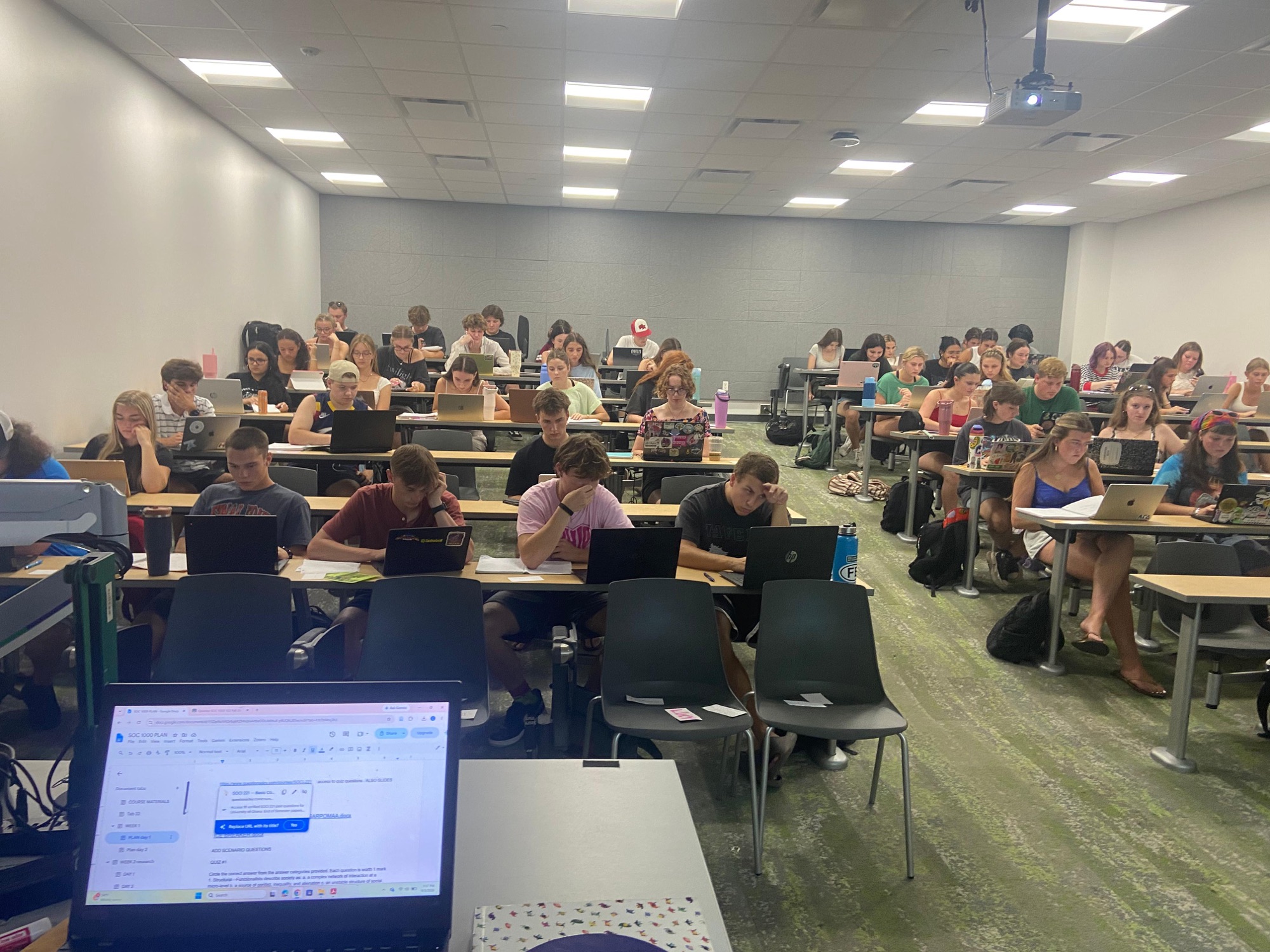 Students working with laptops and notes during a sociology class